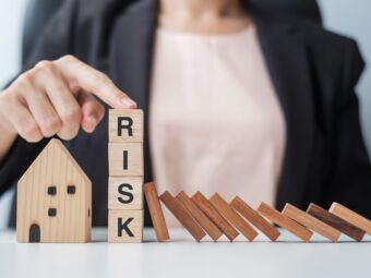 Businessman stop falling wooden blocks and protect house model.